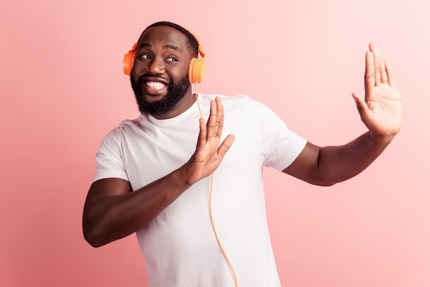 Happy african man smiling listening to music in headphones avoiding show hands