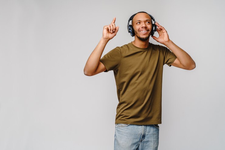 Happy african man smiling listening to music in headphones over grey wall