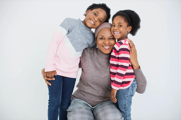 Happy african woman embracing little daughters indoors