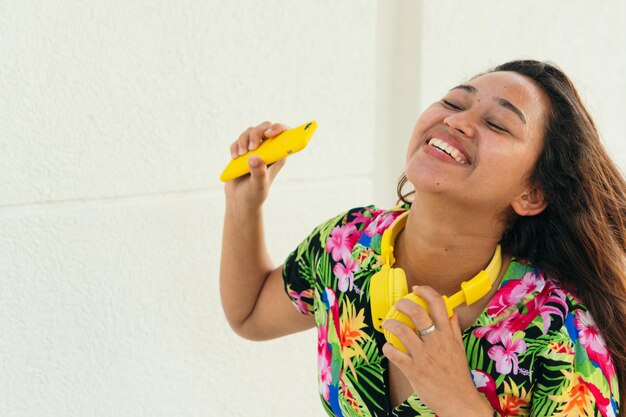 Happy African woman listening to music with earphones against white wall