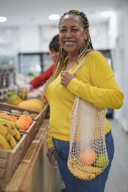 Happy african woman smiling on camera while buying fresh
organic fruits inside supermarket