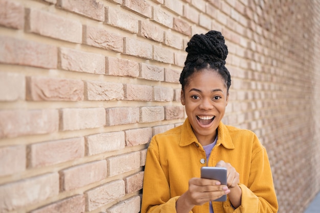 Felice donna africana che utilizza l'app mobile per lo shopping online con il concetto di black friday di ispirazione per le vendite