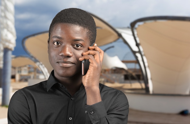 Uomo afroamericano felice che per mezzo di un telefono cellulare