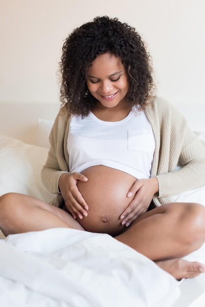 Happy afro woman showing her pregnant belly