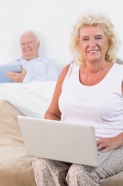 Happy aged couple using a tablet and the laptop