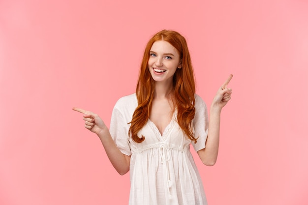 Happy alluring redhead female in white dress, helping out with fashion advice, pointing fingers