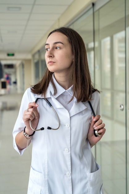 病院の廊下で一人で幸せな若い女性看護師。医学の概念