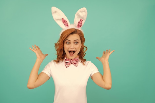 Happy amazed easter woman in bunny ears and bow tie on blue background