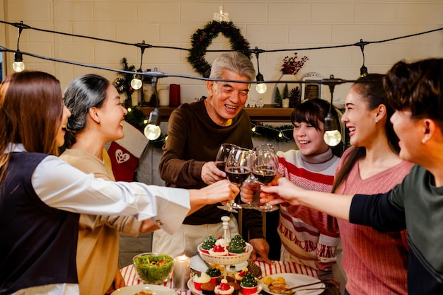 写真 アジア系大家族の幸せで陽気なグループが クリスマスディナーで乾杯と ⁇ 声をあげています