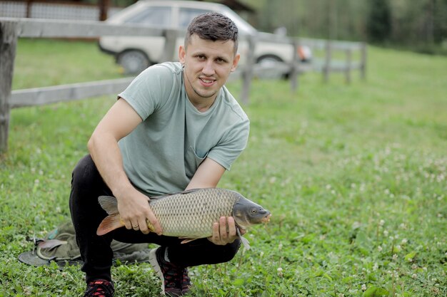 Счастливый рыболов держит трофейный карп