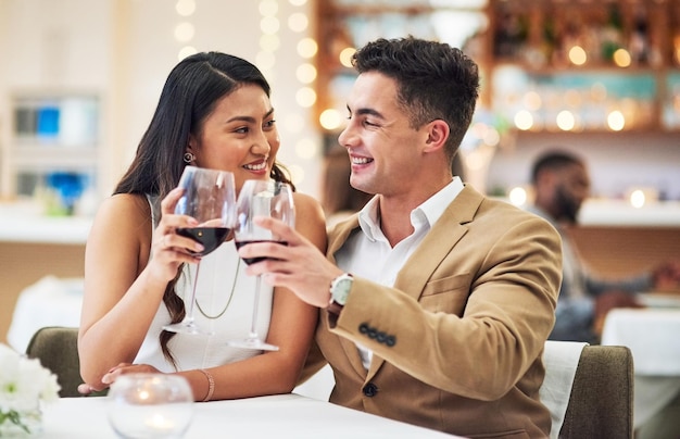 ハッピーアニバーサリーベイビーレストランに座ってお祝いの乾杯をしている愛情のこもった若いカップルのクロップドショット
