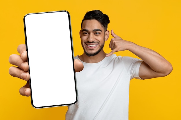 Happy arab guy showing cell phone with blank screen