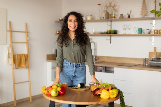 Happy arab woman cooking at home smiling lady preparing healthy meal looking and smiling at camera