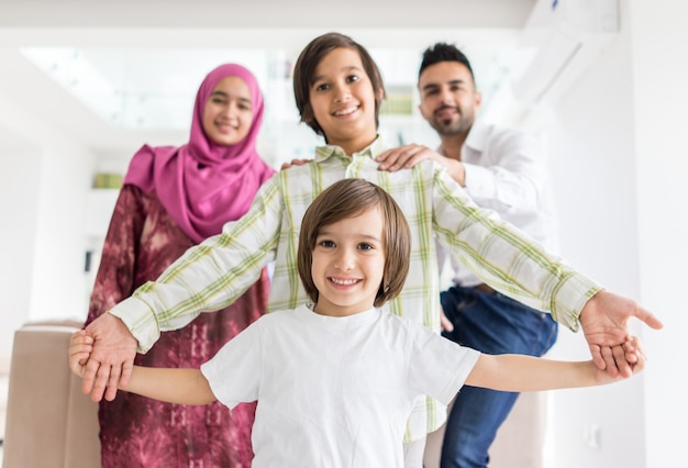現代の家庭でハッピーアラブ人のイスラム教徒の家族が一緒に楽しんで楽しい時間を持つ