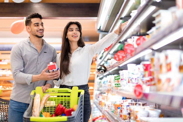 Coniugi arabi felici che acquistano cibo durante la spesa al supermercato