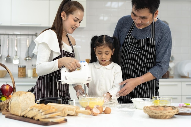 Photo happy asia family with daughter making dough preparing baking cookies daughter help parent preparing the bake family concept