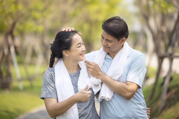 Happy asia senior couple jogging outdoors in park.