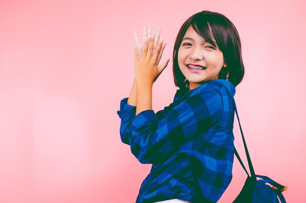 Happy asia young girl with backpack and pink background.