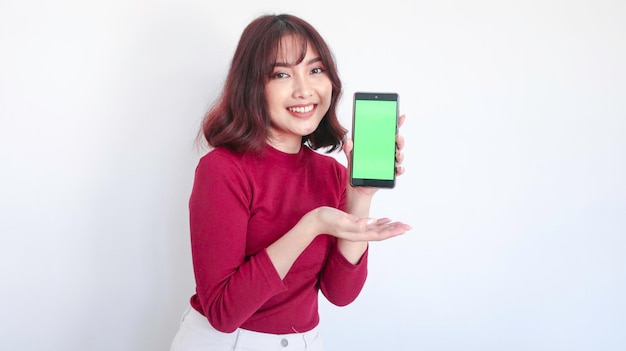 Happy Asian beautiful girl point on green screen phone in white background