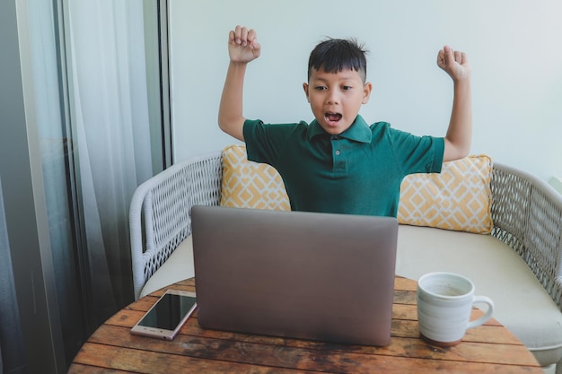 Happy asian boy celebrating while watching online broadcast match using laptop