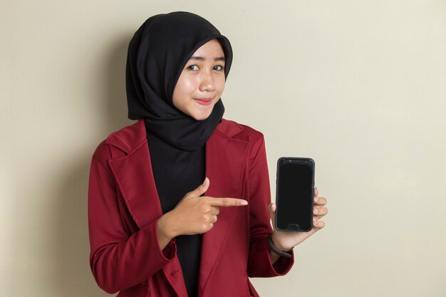 Happy Asian business woman in hijab demonstrating mobile cell phone. Portrait of smiling woman, posing