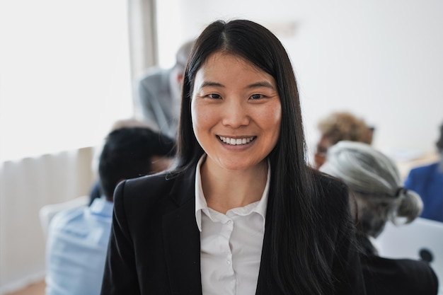 Happy asian business woman smiling on camera inside bank office