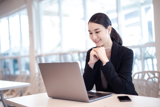 Happy Asian business woman talking by mobile phone