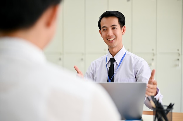 사무실에서 일하는 동안 동료에게 엄지손가락을 보여주는 행복한 아시아 사업가