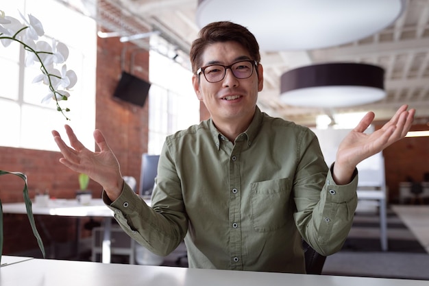 Happy asian businessman sitting at desk talking and gesturing during video call. working in business at a modern office