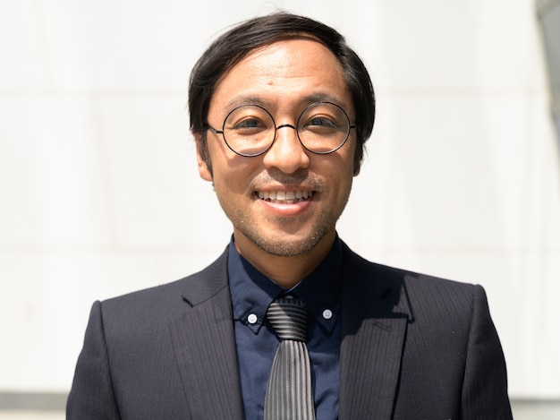 happy Asian businessman smiling on concrete wall