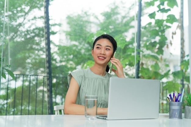 Happy asian businesswoman or creative worker calling on smartphone at office