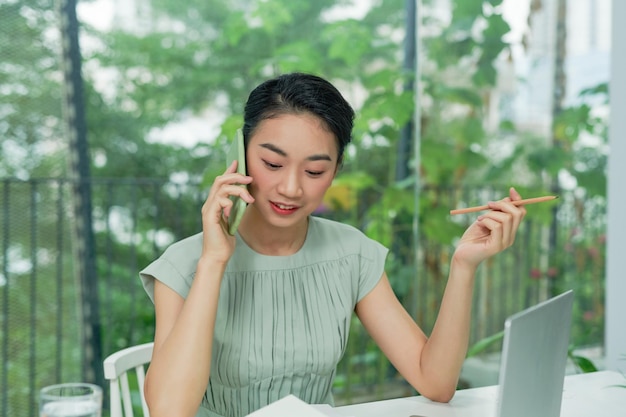 Happy asian businesswoman or creative worker calling on smartphone at office