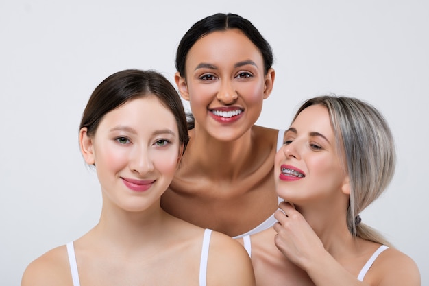 Happy asian, caucasian and african girls with different types of skin in white panties and shirt.