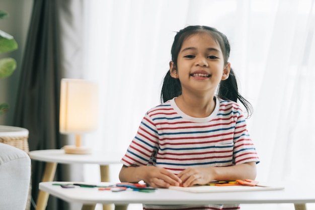 Happy asian child girl drawing with colorful pencils in living room at home