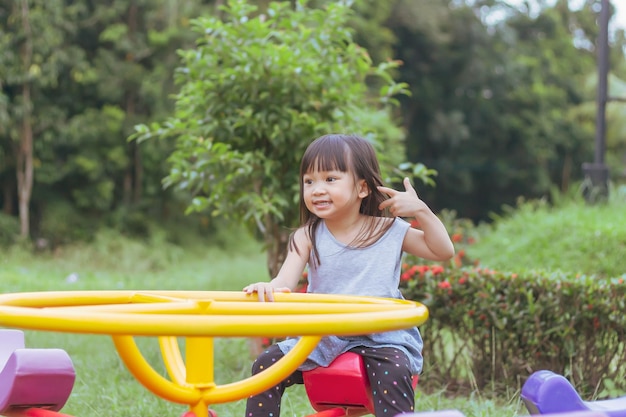 Felice bambina asiatica che gioca con il giocattolo della barra di scorrimento al parco giochi kid and sport