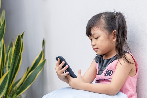 スマートフォンを見て、使用して幸せなアジアの子供の女の子