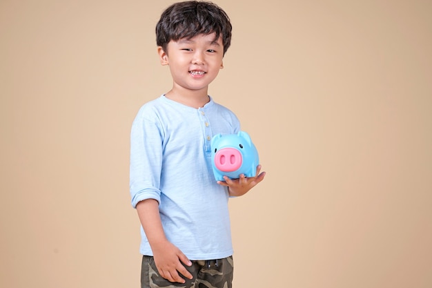 Счастливый азиатский ребенок держит розовую копилку