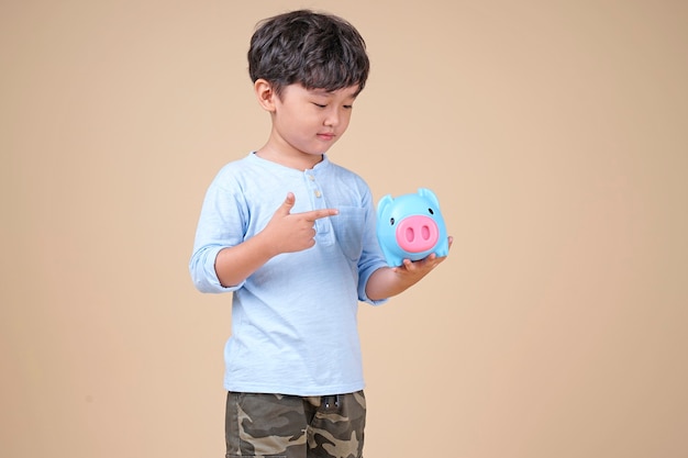 ピンクの貯金箱を保持している幸せなアジアの子供