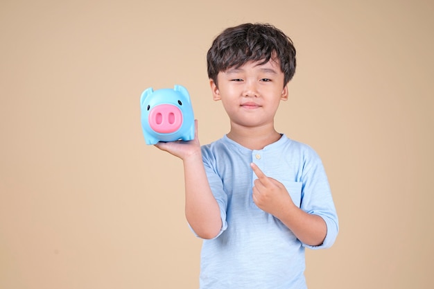 ピンクの貯金箱を保持している幸せなアジアの子供