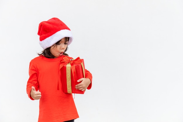 Bambino asiatico felice in cappello rosso della santa che tiene i regali di natale. natale time.on sfondo bianco.