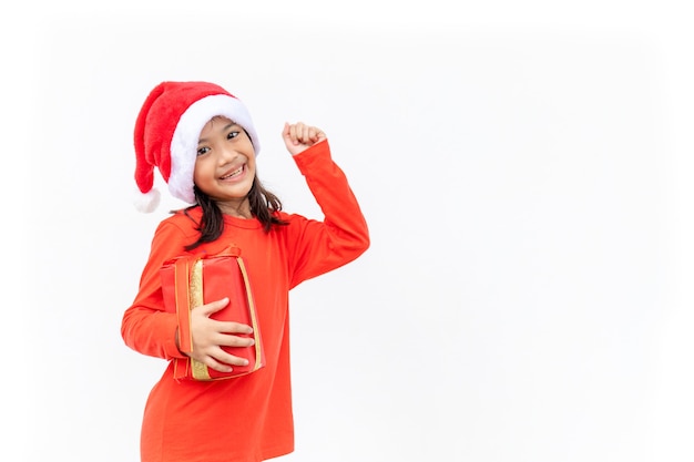 クリスマスプレゼントを保持しているサンタの赤い帽子の幸せなアジアの子供。クリスマスの時間。白い背景に。