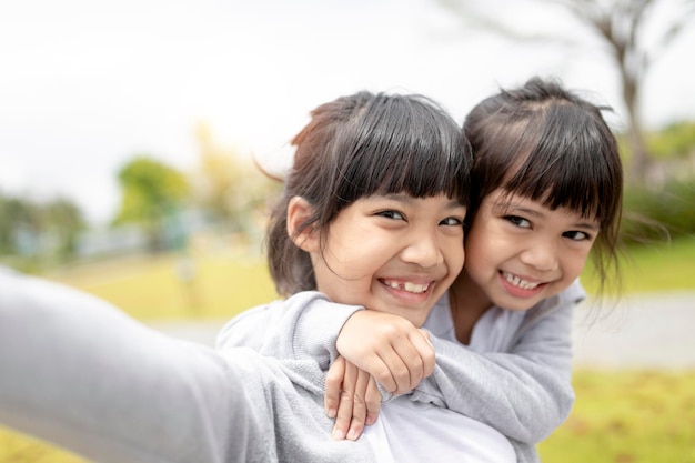 幸せなアジアの子供が公園で自分撮りをします