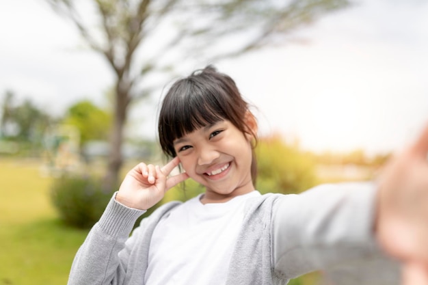 幸せなアジアの子供が公園で自分撮りをします