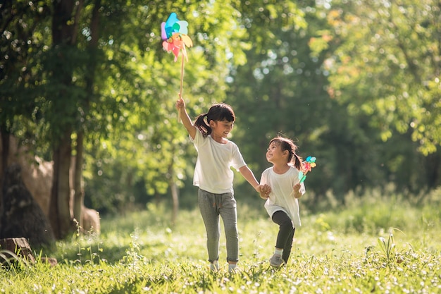 Happy Asian children girl with wind turbine in the garden