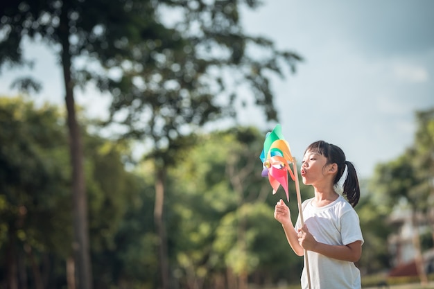 庭で風力タービンを持つ幸せなアジアの子供たちの女の子