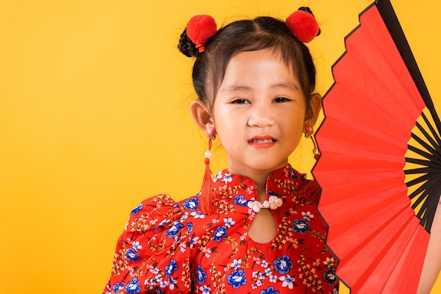 Happy Asian Chinese little girl smile wearing red cheongsam holding fan