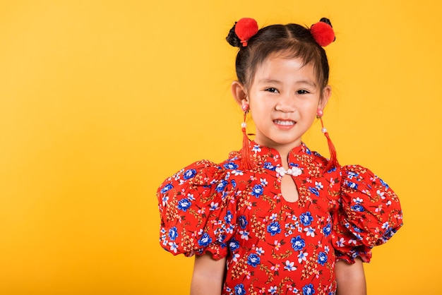 赤いチャイナドレスを着て幸せなアジアの中国の少女の笑顔