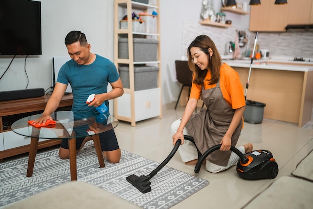 Happy asian couple cleaning their living room together