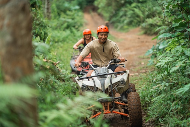 Happy asian couple enjoy their trip riding the atv through the amusement park