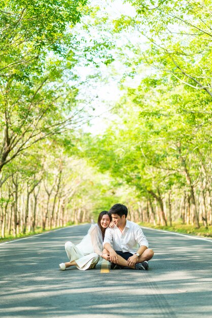 木のアーチと道路上の愛の幸せなアジアカップル